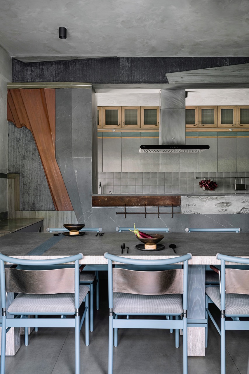 The dining area on the lower level has a monolithic concrete table surrounded by stainless steel chairs, both customdesigned by Multitude of Sins