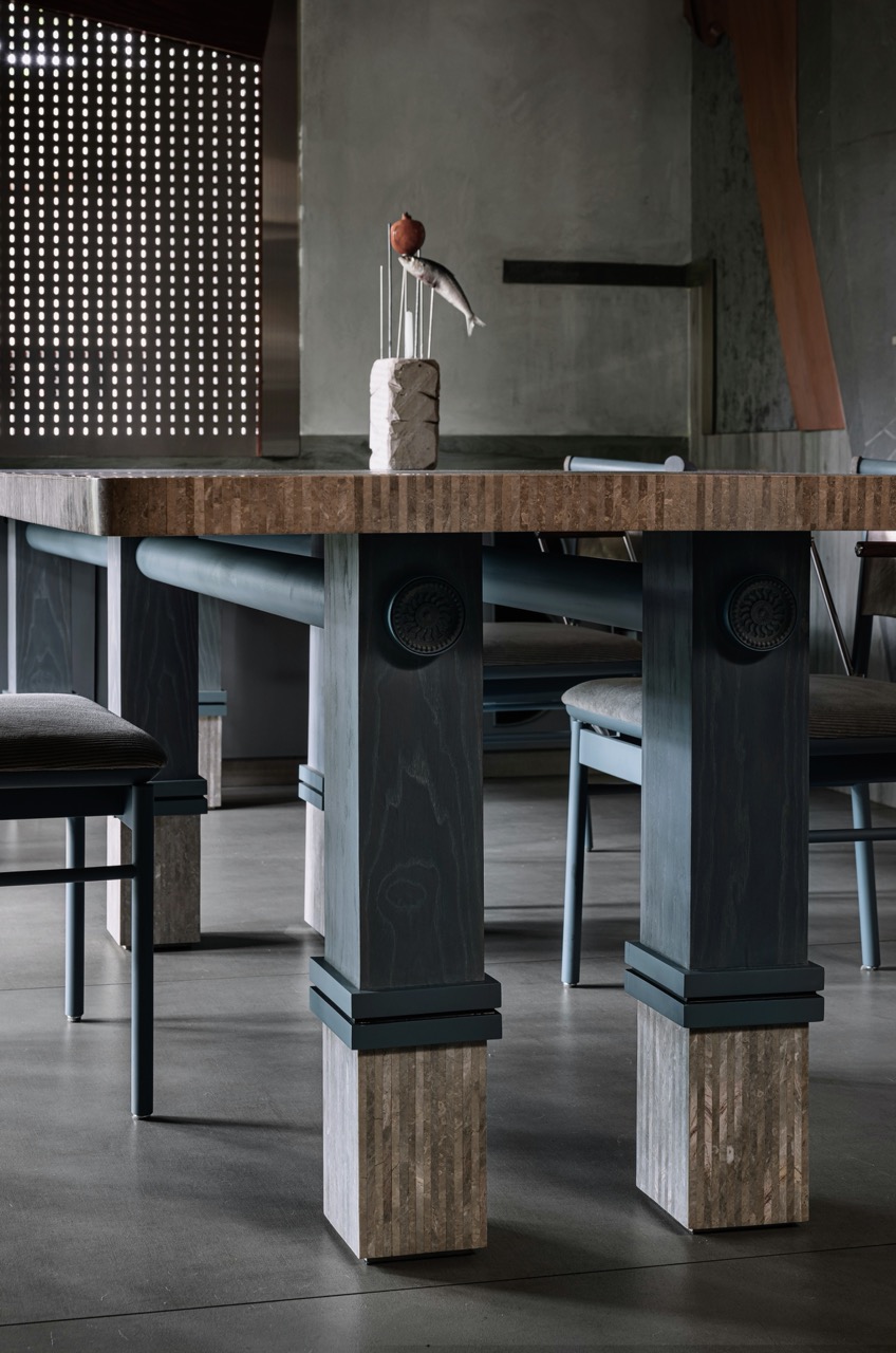 The dining table stands on stained grey legs that mimic tall concrete blocks