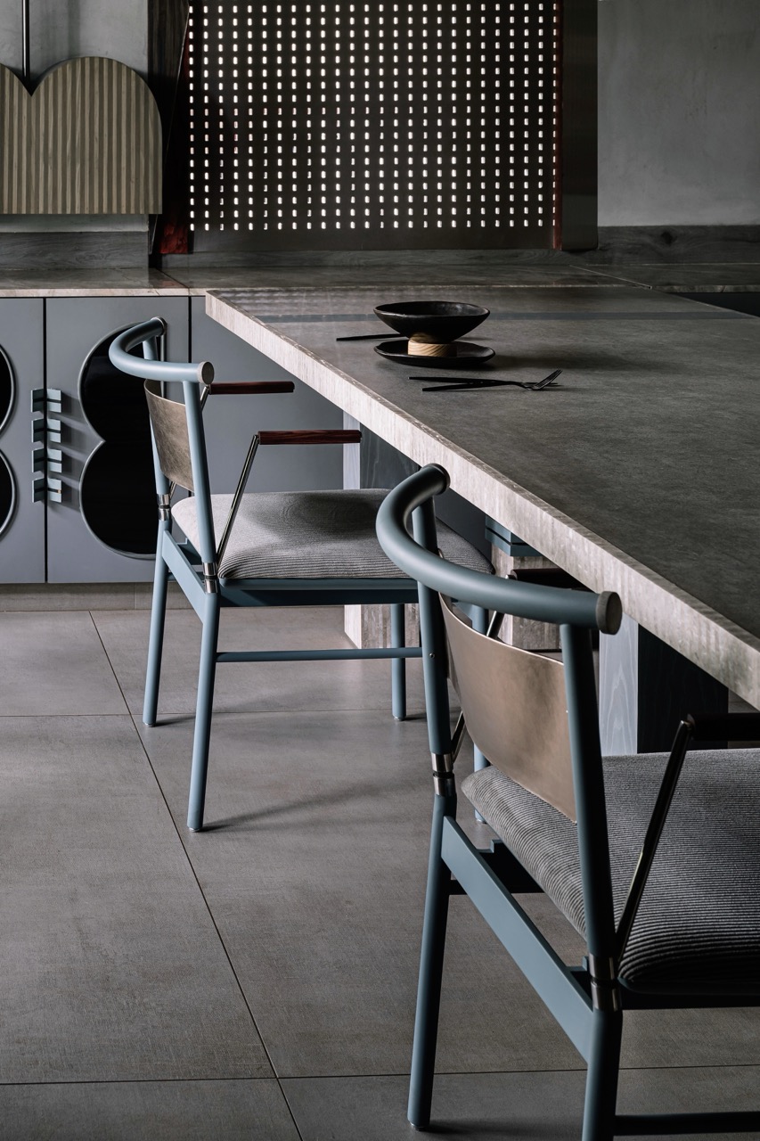 The dining chairs, a softer counterpoint, are painted a dusky blue with metal backrests