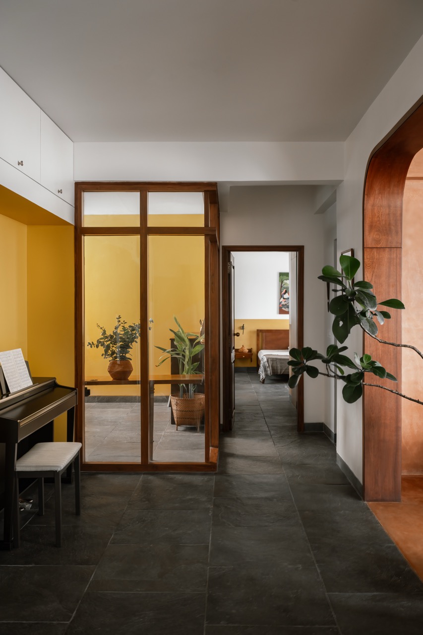 An upright piano sits along the corridor that begins at the living room and connects the wife’s workspace and the guest bedroom