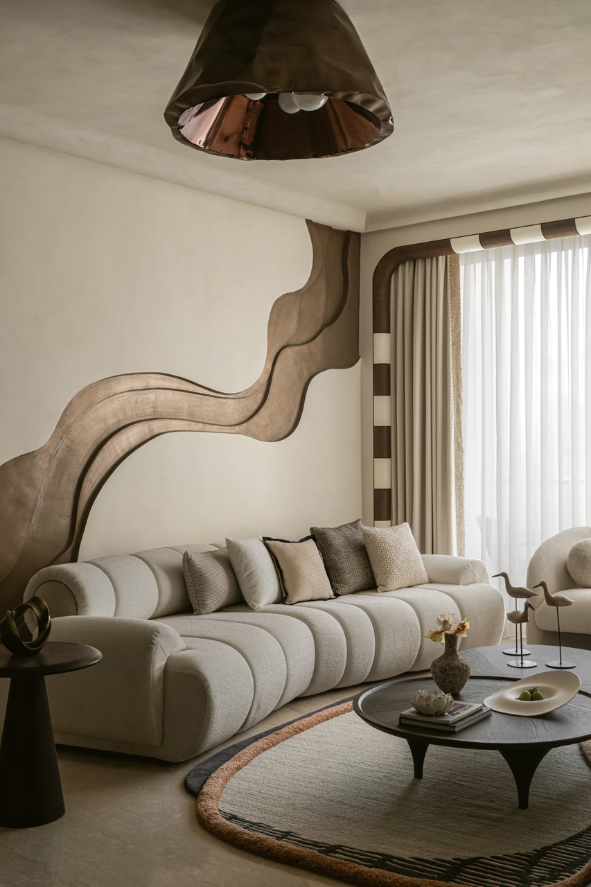 The starting point for for this 1,200 sq ft project was designing this supersized wave motif on the living room wall. All other elements, including this living room chandelier by Nitush · Aroosh, follow the aesthetic of soft curves