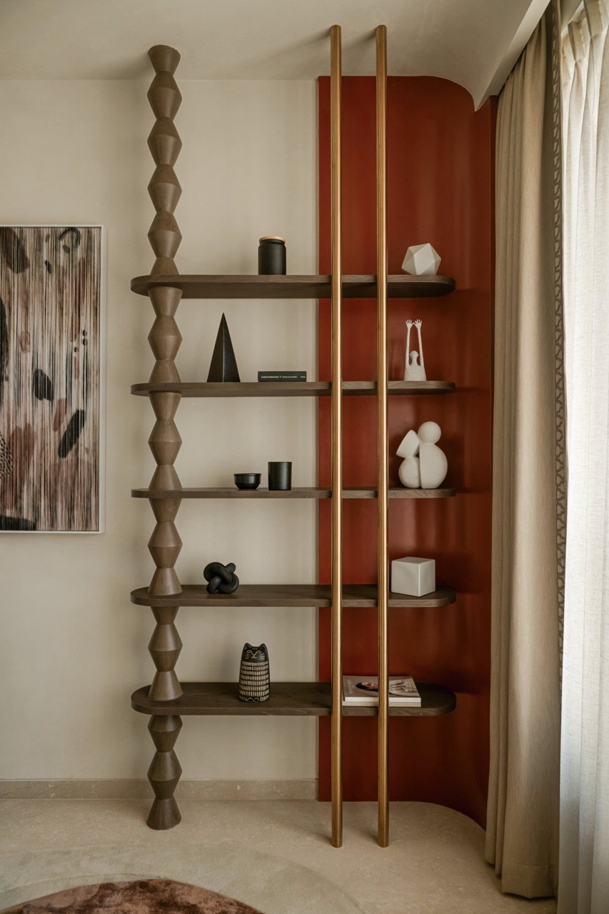 On the other side of the guest room is an open shelving unit with carefully selected objets d’arte that work within the curved format of the space