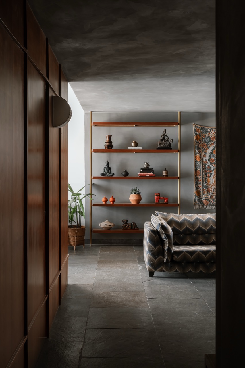 Inviting slow days and relaxed moments, the family lounge showcases wall-hung textiles, terracotta pots, and metallic spiritual sculptures alongside other curios on the display unit