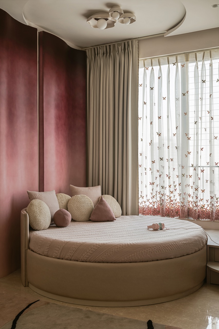 In the daughter’s room, a curved wall that graduates from wine to pink forms a vibrant backdrop to the circular bed