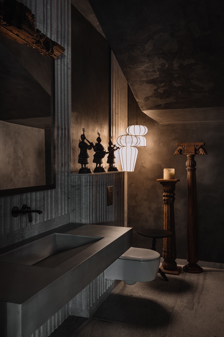 Atmospheric greys define the first bathroom, complemented by wooden pillars and curated antiquities