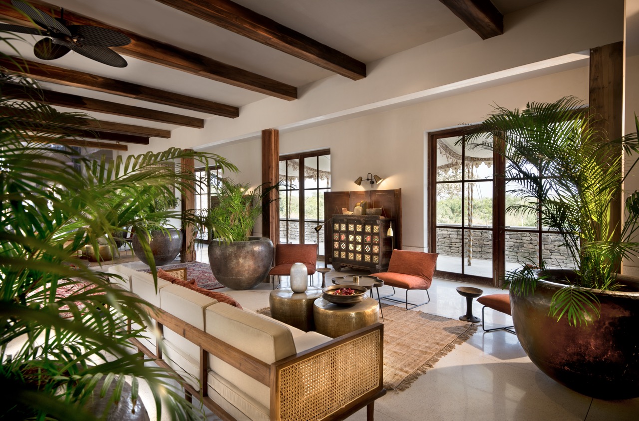 The haveli reception is arranged with low seating, terrazzo flooring, and timber beams, layered with antiques and locally crafted decor objects