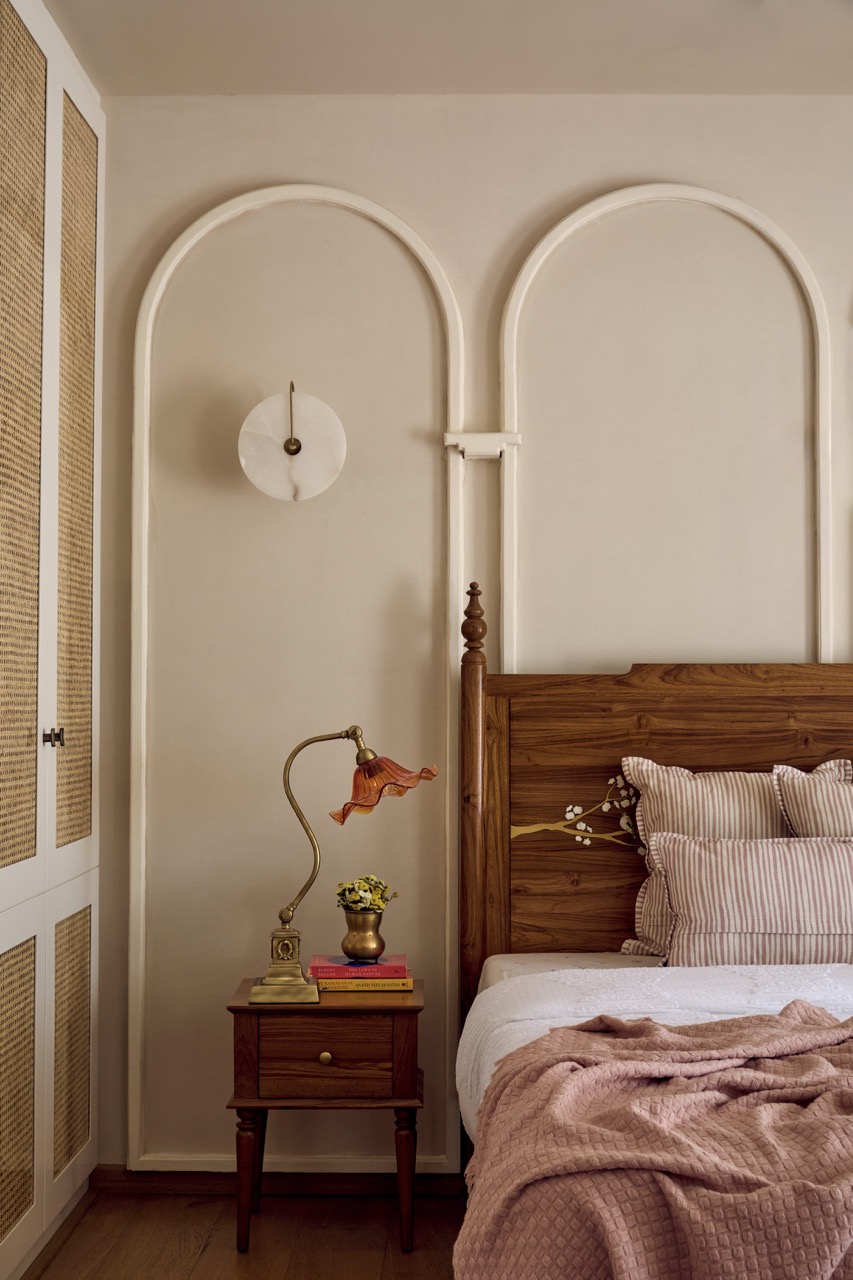 Classic touches meet cosy comfort in the primary bedroom, where an antique lamp from The Hesperus Store, wall lights by Luminary Studio, a Dastkari bed and side tables, wardrobes by Niche Build Solutions, and bedding from Cottons and Satins all come together