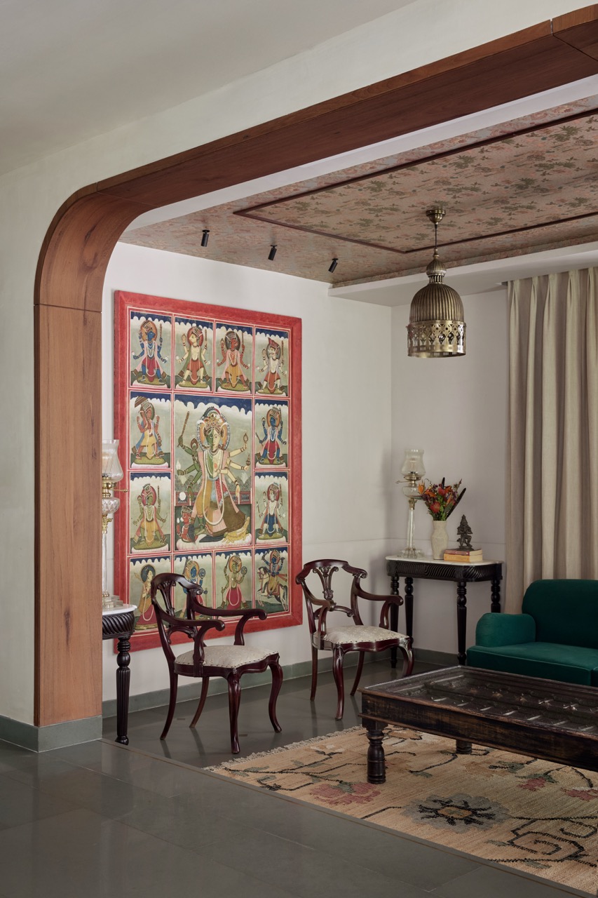 The living room is a kaleidoscope of art and design, featuring chairs and corner consoles from The Hesperus Store, a centre table by The Purple Turtles, and Dasavatara art by Studio Orion. Pendant lights from Inhabit cast a balanced glow over the Sabyasachi for Nilaya wallpaper by Asian Paints above and the Home Neera carpet below