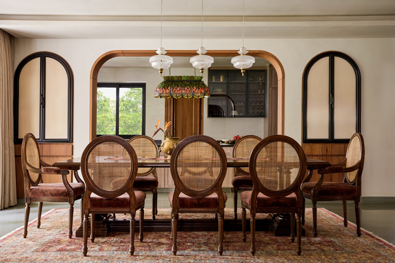 Seating eight, the dining area is a refined oasis of vintage charm, enriched by warm timber, woven cane, aged brass, and layered textiles that soften the light and add tactile depth