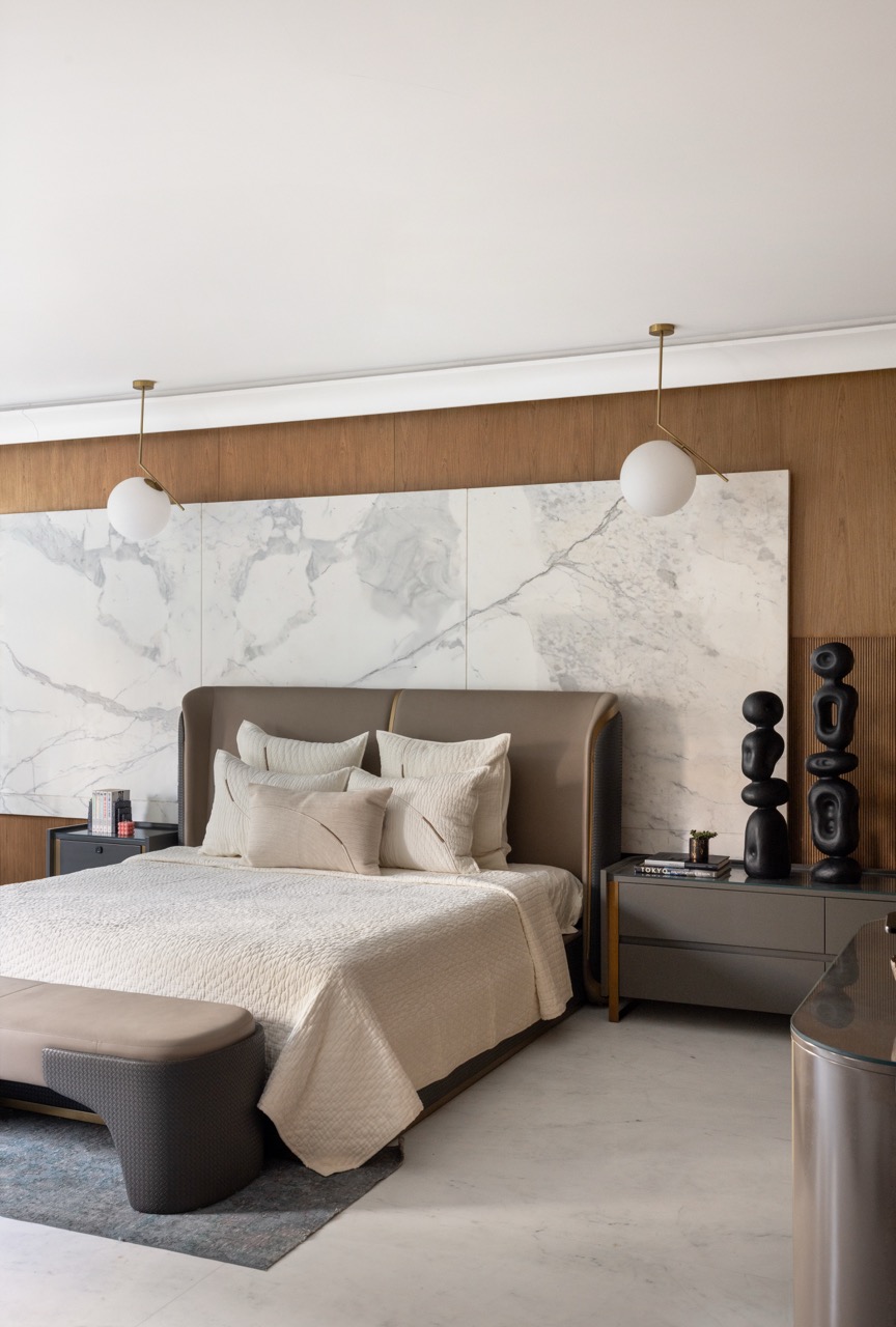 The bedroom is anchored by a calm palette, with lights by Maison du Luxe, an accent wall clad in veneer by Coast to Coast, and bedside sculptures by Muun Home