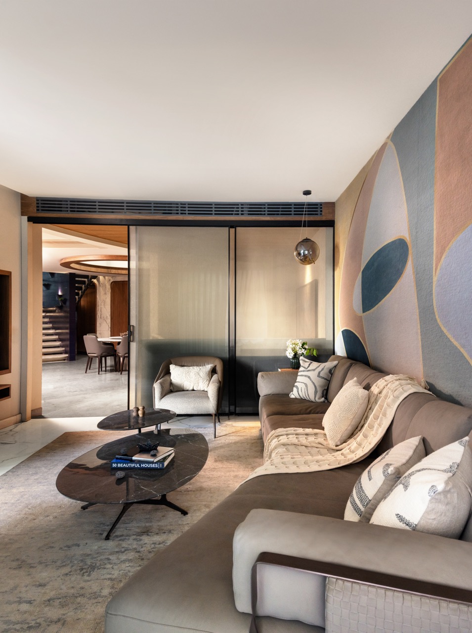 The family lounge opens out through sliding panels, creating a soft transition between shared living spaces, with the right wall clad in Affreschi & Affreschi wallpaper