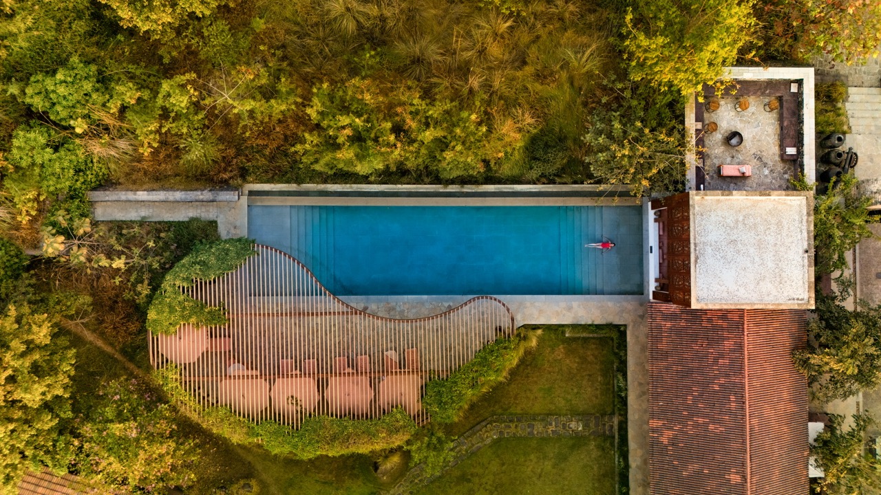 Seen from above, Aramness Gir reveals its layout of courtyards, water, and built forms, set within dense forest landscape and shaped by soft, curving edges