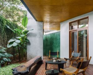 The deck opens to a green patch, with furniture by Kayu and wood flooring that blends into the landscape. The ochre ceiling and green corrugated wall at the far end complements the earthy nature of the space