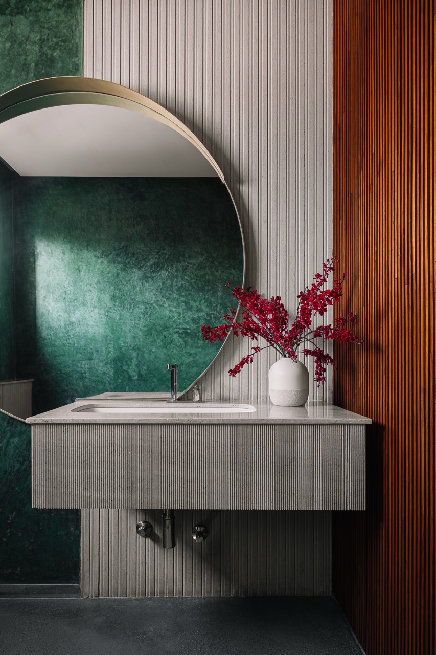 The terrace powder room combines ribbed sandstone, fluted white marble, and green oxide, with fluted wood at the entrance adding warmth to the compact space