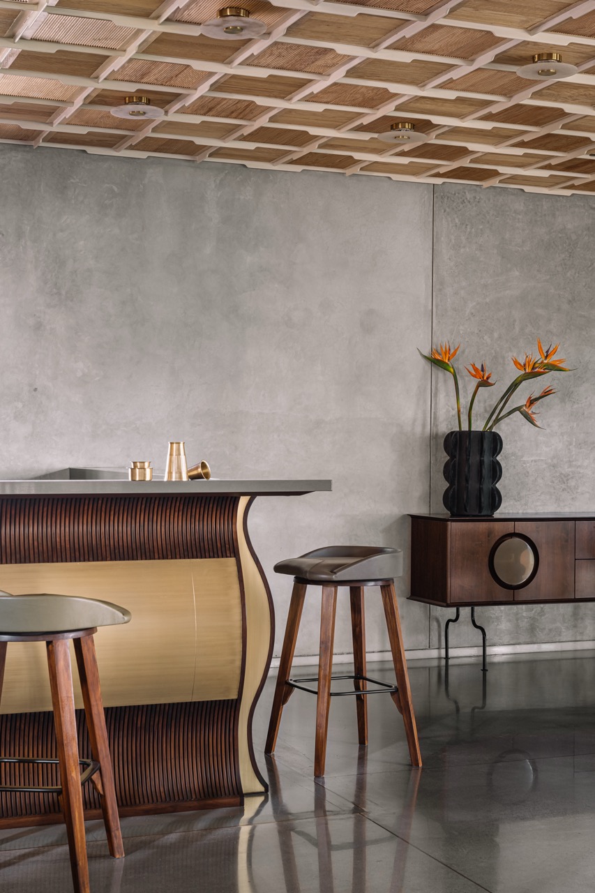 A custom open kitchen counter in fluted wood and brass by Timberworks India by Virasp Bativala sits within the dining space, its form echoing the language of the staircase