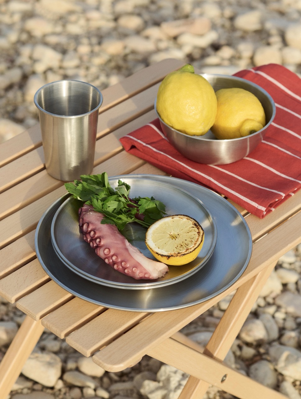 A detail of the stainless steel tableware and striped linens
