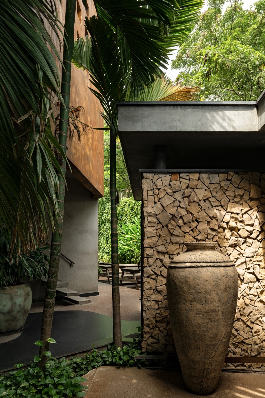 This corner captures the project’s materiality, a broken-stone wall, and slender palms