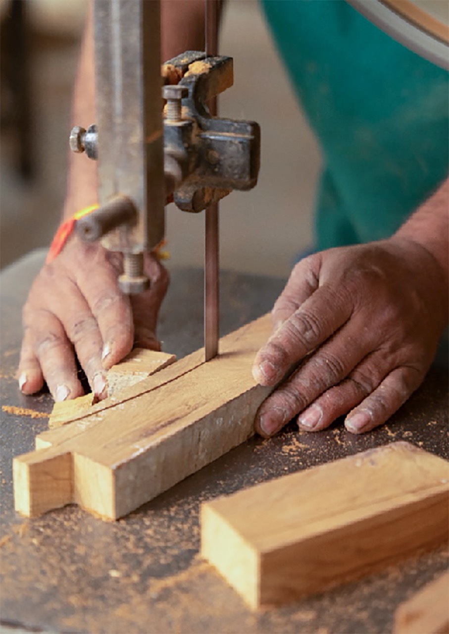 An artisan shaping reclaimed teak for the Ligero dining chair